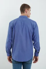 Camisa azul de manga larga con cuello clásico, cierre con botones y bolsillo en el pecho.