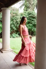 Falda larga de lino color salmón, con diseño de múltiples niveles de volados que aportan volumen y movimiento. Presenta una cintura ajustada y caída fluida.