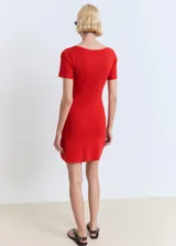 Vestido corto de punto fino color rojo, con escote en pico y detalle de lazos frontales. Presenta mangas cortas y un diseño evasé.