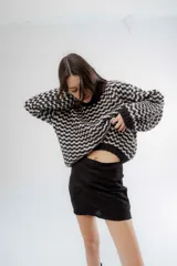 Buzo de punto grueso con diseño bicolor en patrón geométrico, de calce holgado y mangas largas.