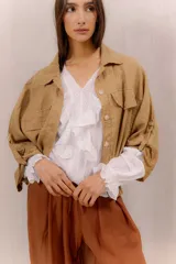 Campera liviana de lino color tostado, con cierre frontal de botones, bolsillos ojal en el pecho y mangas anchas con presilla y botón en los puños.