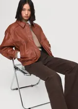 Chaqueta de cuero de ovino en color marrón, de diseño oversize con cuello clásico, cierre frontal con botones a presión y bolsillos frontales con solapa.