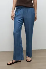 Pantalón de corte recto confeccionado en lyocell, color azul jean medio, con cintura elástica con cordón de ajuste y bolsillos laterales.