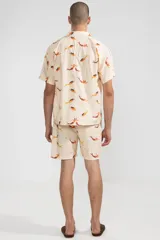 Short de algodón color crema con estampado de sirenas color naranja y amarillo, cintura elastizada con cordón ajustable, dos bolsillos laterales y un bolsillo trasero tipo parche.