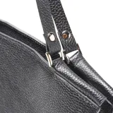 Cartera tipo tote de cuero negro con textura granulada, diseño trapezoidal y logo de la marca grabado en el centro. Cuenta con correas largas para llevar al hombro.