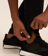Pantalón deportivo Get Over de color negro, con cintura elástica, cordón de ajuste, bolsillos con cremallera, bandas laterales y cremallera en el bajo.