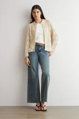 Cardigan de punto calado color beige, con cuello redondo y cierre frontal de botones.