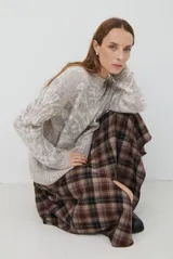 Falda midi de corte irregular con diseño a cuadros en tonos marrones, negros y beige. Presenta una silueta acampanada con caída fluida.