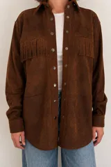 Camisa tipo overshirt de gamuza marrón óxido con flecos en el pecho, cuello camisero, bolsillos delanteros y cierre frontal de botones metálicos a presión.
