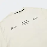 Remera de algodón color blanco hueso con corte oversize, hombros caídos y cuello redondo. Presenta un estampado minimalista en el pecho con tipografía y caracteres asiáticos, y un logo bordado en la manga.