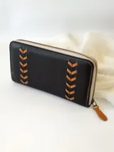 Billetera negra de cuero con cierre metálico, diseño con pespuntes en forma de espiga y logo de la marca en etiqueta de cuero. Incluye monedero interno y espacio para billetes extendidos.