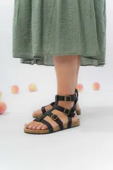 Sandalia de cuero sintético color negro, con múltiples tiras y hebillas metálicas ajustables. Base de corcho liviana y plantilla anatómica forrada en eco-cuero.