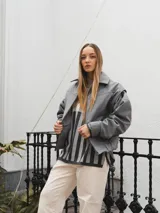 Campera gris con cierre frontal, cuello camisero y mangas largas con puños elásticos.