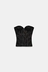 Corsé de encaje negro con escote corazón, hombros descubiertos y varillas interiores para estructura. Cuenta con cierre lateral mediante cremallera oculta.