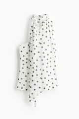 Top entallado de malla transparente color blanco con lunares negros. Presenta un escote asimétrico, un solo bretel y tiras anchas que se atan al cuello. Incluye forro de punto.