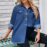 Campera tipo sobrecamisa de denim en tono azul claro, con corte oversize, cuello italiano, cierre frontal con botones metálicos, bolsillos frontales con solapa y ruedo con detalle desflecado.