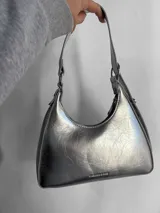 Cartera baguette plateada con textura craquelada, asa corta y logo "Fashion & Bag" en el frente.