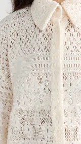 Camisa color blanco hueso con cuello clásico, tapeta con botones en la parte delantera y corte recto ligeramente oversize. Diseño con acabado de encaje.