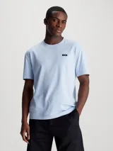 Remera Calvin Klein de punto de algodón regenerativo, color celeste, con corte regular, cuello redondo y mangas cortas. Presenta una lengüeta con el logo de Calvin Klein en el pecho.