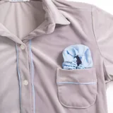 Pijama de dos piezas color rosa pálido, confeccionado en terciopelo. La camisa es de manga larga con botones frontales y bolsillo en el pecho. El pantalón es de corte recto con cintura elástica.