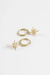 Aros de acero quirúrgico plateado tipo argolla con dije colgante en forma de estrella de ocho puntas que incluye un strass en el centro.