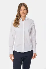 Camisa blanca de corte entallado, manga larga con puños abotonados y cuello clásico. Presenta cierre frontal con botones ocultos bajo una tapeta.