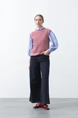 Chaleco tejido de algodón y acrílico, color rojo y blanco con patrón geométrico. Tiene cuello redondo y bordes acanalados en rojo.