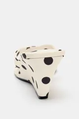 Sandalia de mujer con tacón tipo cuña, base color crema con estampado de lunares negros. Presenta una tira delantera con posición para el dedo y punta redonda.