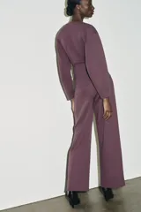 Jersey de cuello redondo y manga larga, confeccionado en tejido de punto elástico con trama compacta. Presenta un diseño con pinzas en la cintura que le otorgan una silueta entallada.