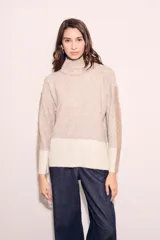 Sweater de punto con cuello alto, corte holgado y diseño color block en tonos beige y blanco.