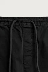 Bermuda cargo color negro de corte relaxed fit, confeccionada en tejido de algodón con elasticidad y efecto lavado. Cuenta con cintura elástica ajustable con cordón, bolsillos frontales y bolsillos laterales tipo cargo con solapa en las perneras.