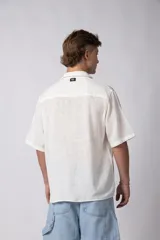 Camisa de manga corta confeccionada en lino, con cuello clásico y cierre frontal de botones. Presenta un corte relajado y textura liviana.