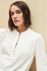 Camisa verde claro de viscosa suave, con cuello mao y botonadura parcial al frente. El detalle de frunces en los hombros y los puños abotonados le suman delicadeza y estilo.