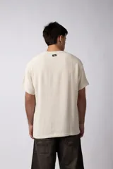 Remera de corte regular confeccionada en una mezcla de rayón y lino con textura entramada. Presenta cuello redondo, mangas cortas y un diseño de inspiración rústica y liviana.