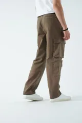 Pantalón cargo de canvas color marrón, con tiro medio, múltiples bolsillos laterales y traseros, y cierre frontal con botón y cremallera.