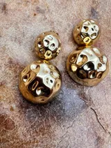Par de aros dorados con diseño de doble esfera texturizada.