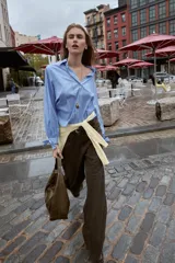 Camisa corta de manga larga, color celeste con finas rayas blancas verticales. Posee cuello solapa y puños anchos ajustados con lazos del mismo tejido.