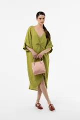 Vestido midi de lino color marrón, de corte amplio y silueta asimétrica con escote en V y detalle fruncido en el centro del frente. Presenta mangas cortas holgadas con vuelta y diseño relajado.