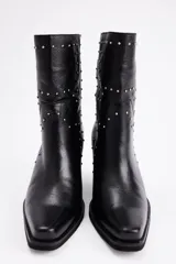 Bota de caña media confeccionada en cuero vacuno negro, con diseño de estilo western, punta cuadrada y detalle de tachas metálicas plateadas distribuidas en la superficie. Cuenta con un taco cuadrado de madera.