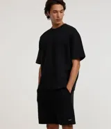 Bermuda masculina de algodón con felpa, color negro, corte slim fit. Presenta cintura elástica con cordón ajustable, bolsillos y etiqueta aplicada.