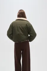 Campera puffer de poliamida color verde militar, con interior y detalles en corderito color crema. Presenta cuello alto, cierre frontal con botones a presión y mangas largas.