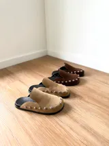 Zuecos color beige con tachas plateadas, base negra y plantilla con el logo de la marca.