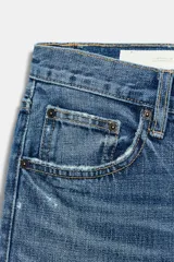 Jeans de tiro medio con corte straight, color azul con efecto lavado y roturas sutiles, cinco bolsillos y cierre frontal con cremallera y botón metálico.
