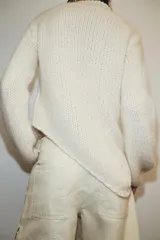 Jersey de punto grueso con cuello redondo, manga larga y diseño de bajo asimétrico.