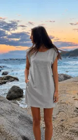 Vestido corto gris melange de corte recto y holgado, con cuello redondo, sisas amplias y bolsillos laterales.