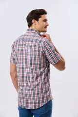 Camisa de manga corta con estampado de cuadros en tonos azules, rojos y blancos, cuello con botones y bolsillo ojal en el pecho con logo bordado.
