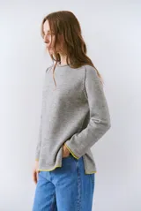 Buzo de tejido de punto color beige, con corte relajado, cuello redondo y mangas largas. Presenta detalles de terminaciones en color azul marino en los puños y en el ruedo inferior.