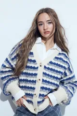 Cardigan de tejido de punto con diseño de rayas horizontales en tonos azul, gris y crema. Presenta escote en V, cierre frontal con botones grandes y mangas largas con puños anchos acanalados.