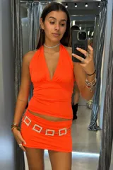 Top de escote halter con diseño ajustado al cuerpo y espalda descubierta, confeccionado en tela elástica de color naranja neón.