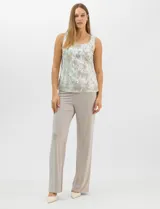 Conjunto de tres piezas compuesto por una musculosa de escote redondo, un cardigan abierto de mangas 3/4 y un pantalón de pierna ancha. La musculosa y el cardigan presentan un estampado abstracto con hilos metalizados, mientras que el pantalón es de color liso con cintura elástica.